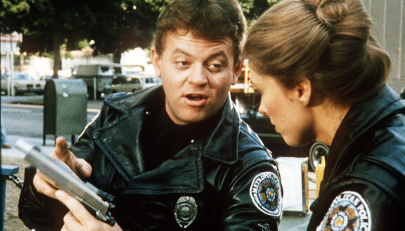 Tackleberry esitteli mielellään isoja aseitaan. Kuva elokuvasta Poliisiopisto II: Eka komennus (1985).