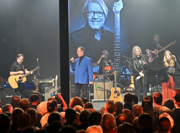 Olli Keskinen juontaa muistokonsertin. Kuvan vasemmassa reunassa myös Heikki Hela.