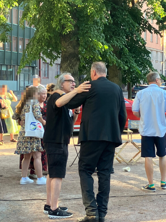 Ilkka Vainio lähestulkoon vaati Esaa esittämään onnittelulaulun Aliisalle, joka poseeraa Esan takana mekossaan.