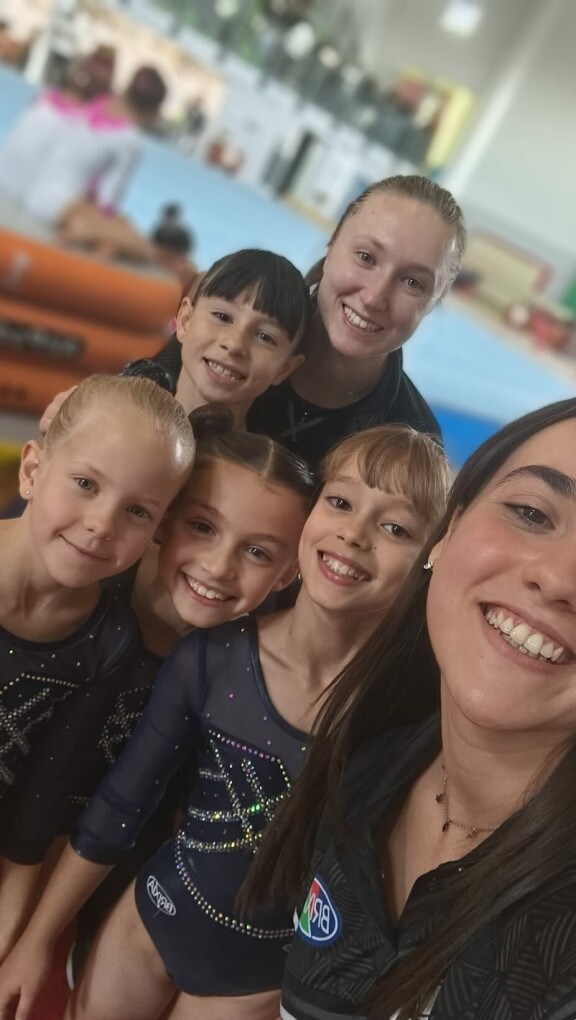 Joukkue valmentajineen hymyili leveästi kisahuuman keskellä. Rianna laitimmaisena vasemmalla.