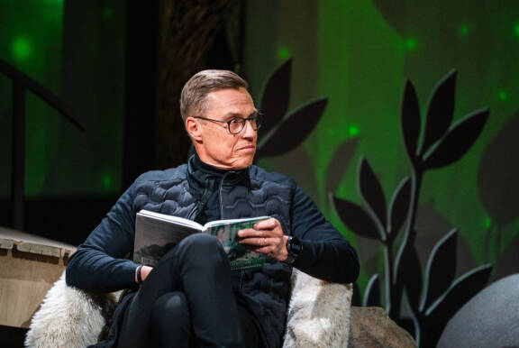Tasavallan presidentti Alexander Stubb luki muumeja sekä ruotsiksi että suomeksi. Alexander Stubb istuu kirja käsissään.