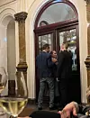 Lukijan mukaan JP ja Netta yrittävät poistua putelin kanssa ulos ravintolasta.