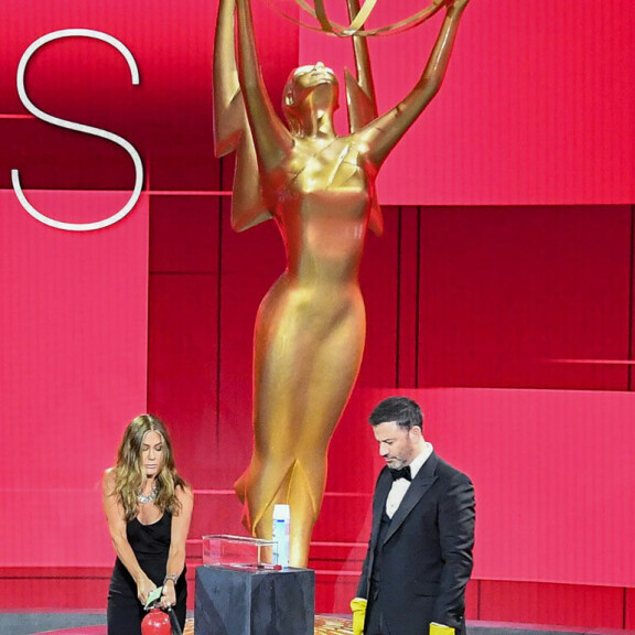 Näyttelijä Jennifer Aniston sammuttamassa tulipaloa, kun Jimmy Kimmel katselee vierestä. Jennifer Aniston ja Jimmy Kimmel