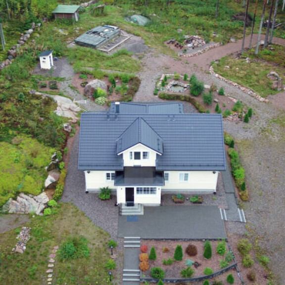 Taloa ympäröi suuri ja vihreä piha-alue. Kuvassa näkyvä kukkapenkki on paikka, josta kohuttu rahakätkö löytyi vuonna 2014. aarnio