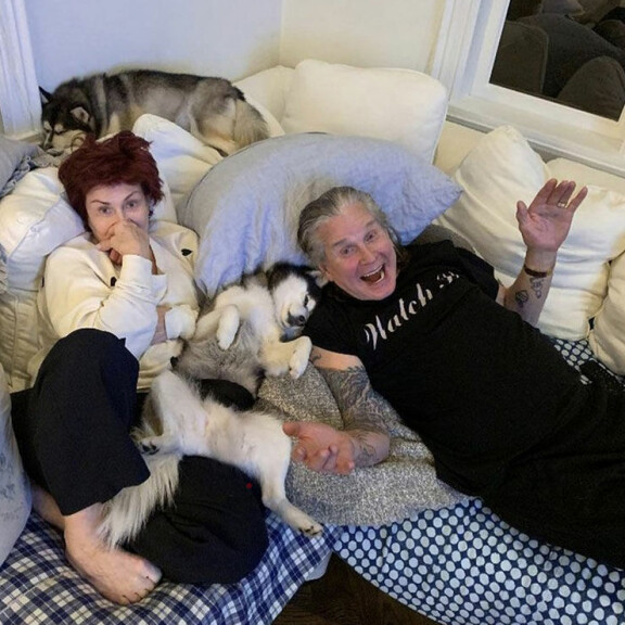 Viriili pariskunta sohvalla loikoilemassa koirien kanssa joulukuussa. Sharon ja Ozzy Osbourne