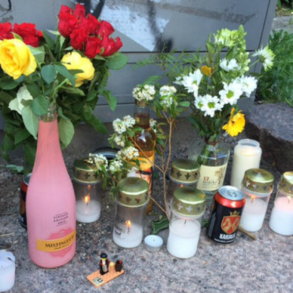 Kuolleen puliukko-Arskan muistopaikka täyttyy lahjoista: tupakkaa, kaljaa, viinipullo, Lego-ukko... Puliukko-Arskan muistopaikka.